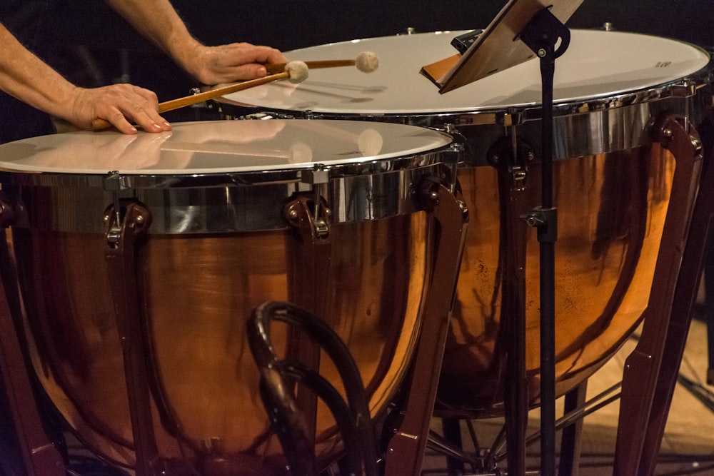 pessoa segurando paus na frente de tambores de percussão