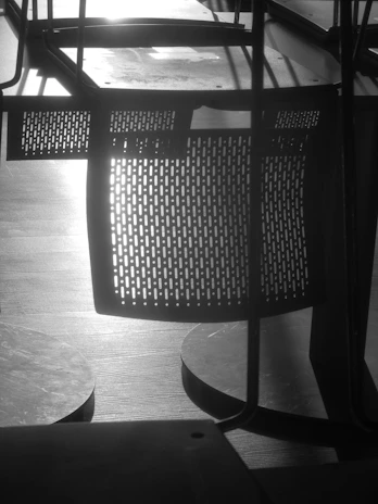 Black and white photo of a custom wooden chair and table set in a cozy workshop.