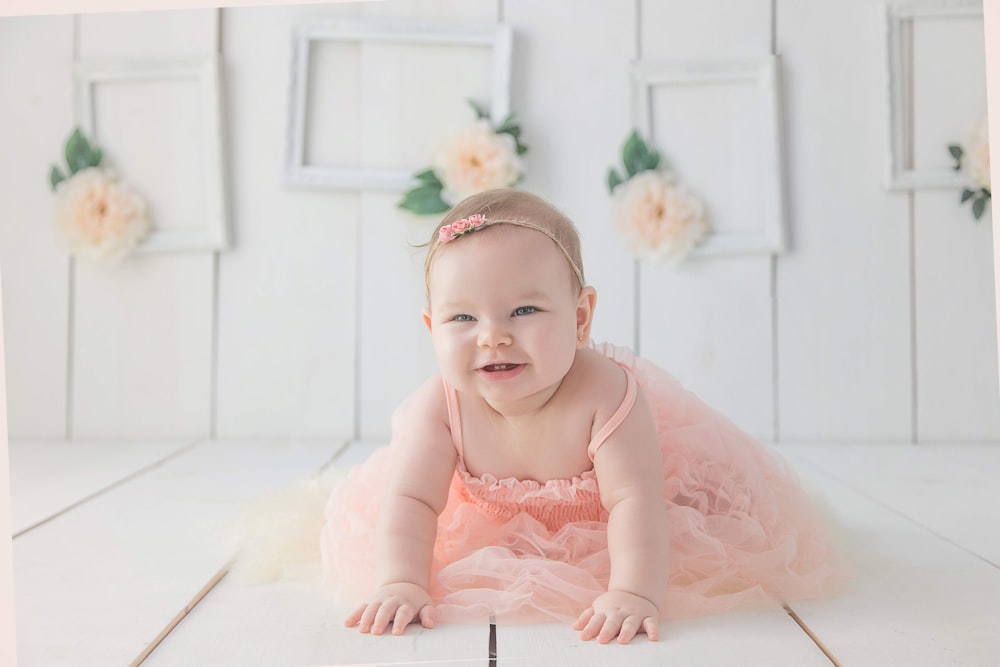 niña arrastrándose por el suelo blanco mientras sonríe