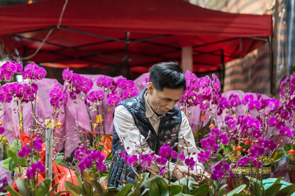 man in black vest surrounded by purple petaled flowers