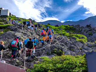 Group of travelers sitting on gray rocks with scenic Mount Fuji view in the background during a hiki