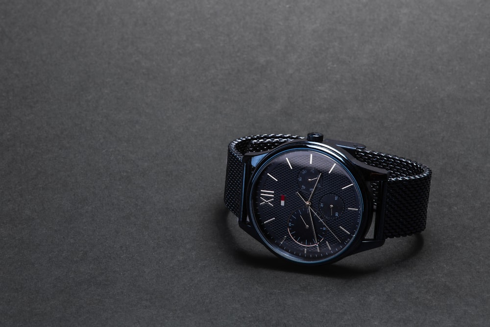 round black Tommy Hilfiger chronograph watch on black surface