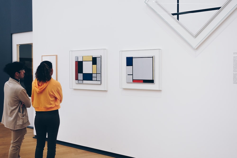 man and woman standing facing painting inside room