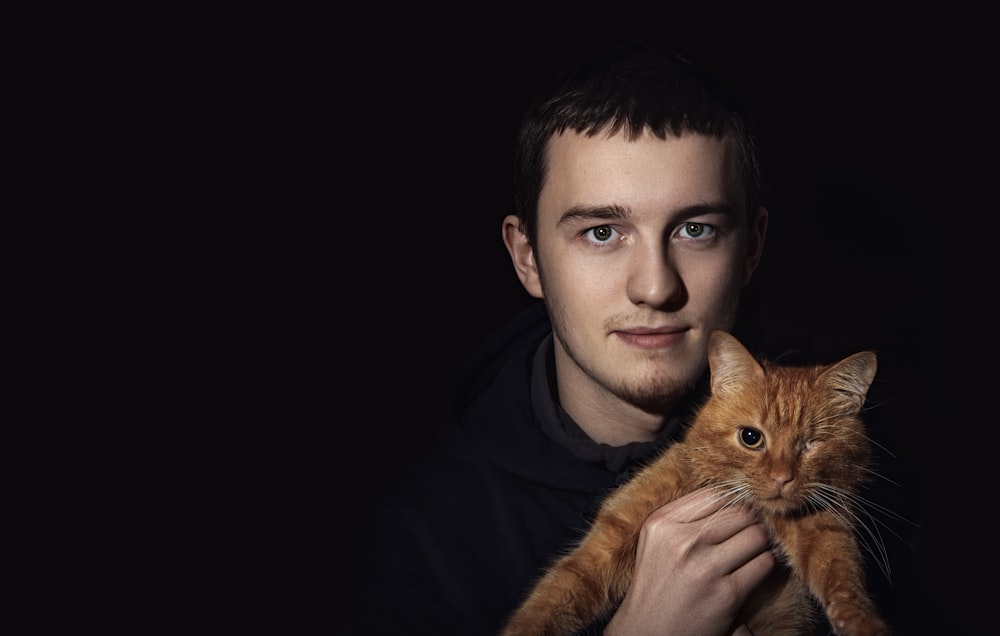 man carrying orange tabby cat