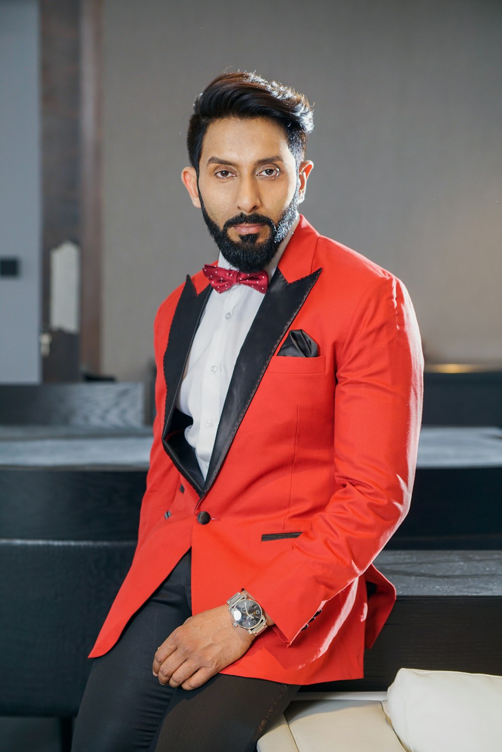 man in red and black peaked-lapel suit sitting on sofa