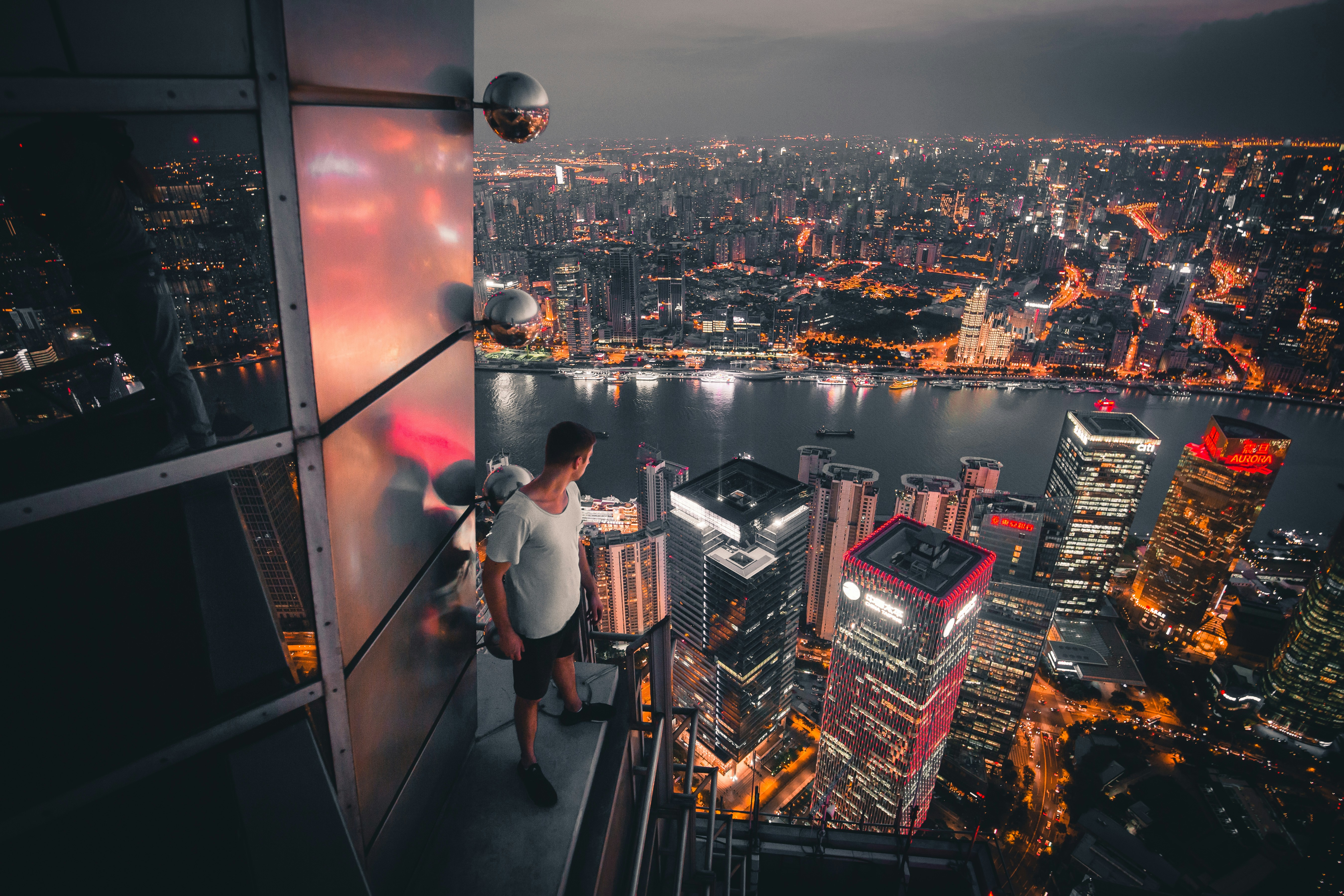 Man Standing At Buildings Rooftop Overlooking City Photo Free Landscape Image On Unsplash