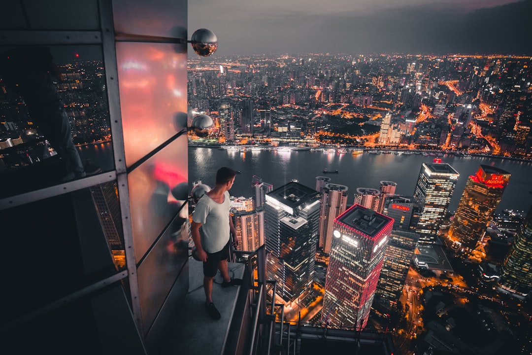 man standing at buildings rooftop overlooking city