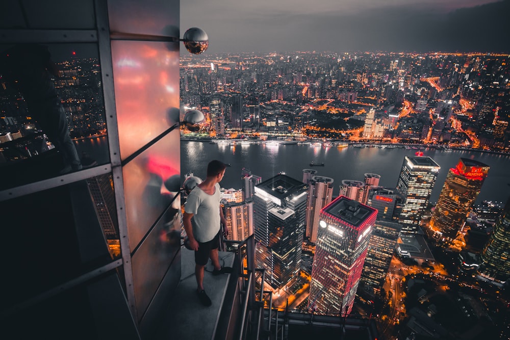 man standing at buildings rooftop overlooking city