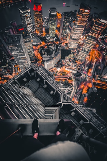 A dynamic aerial drone shot capturing a futuristic neon-lit cityscape at night with glowing fractal patterns overlay.