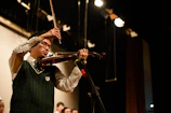 A young violinist concentrating deeply during a Crescendo Academy recital under warm stage lights.