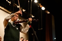 Violinist performing on stage with soft spotlight in a classical setting