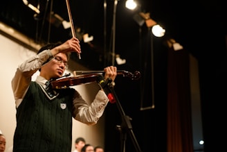 A professional female violinist performing passionately on stage with a warm spotlight.