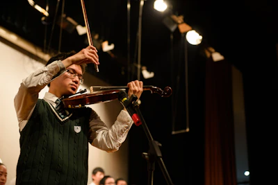 An experienced violinist performing a vibrant Carnatic concert on stage with expressive emotion.