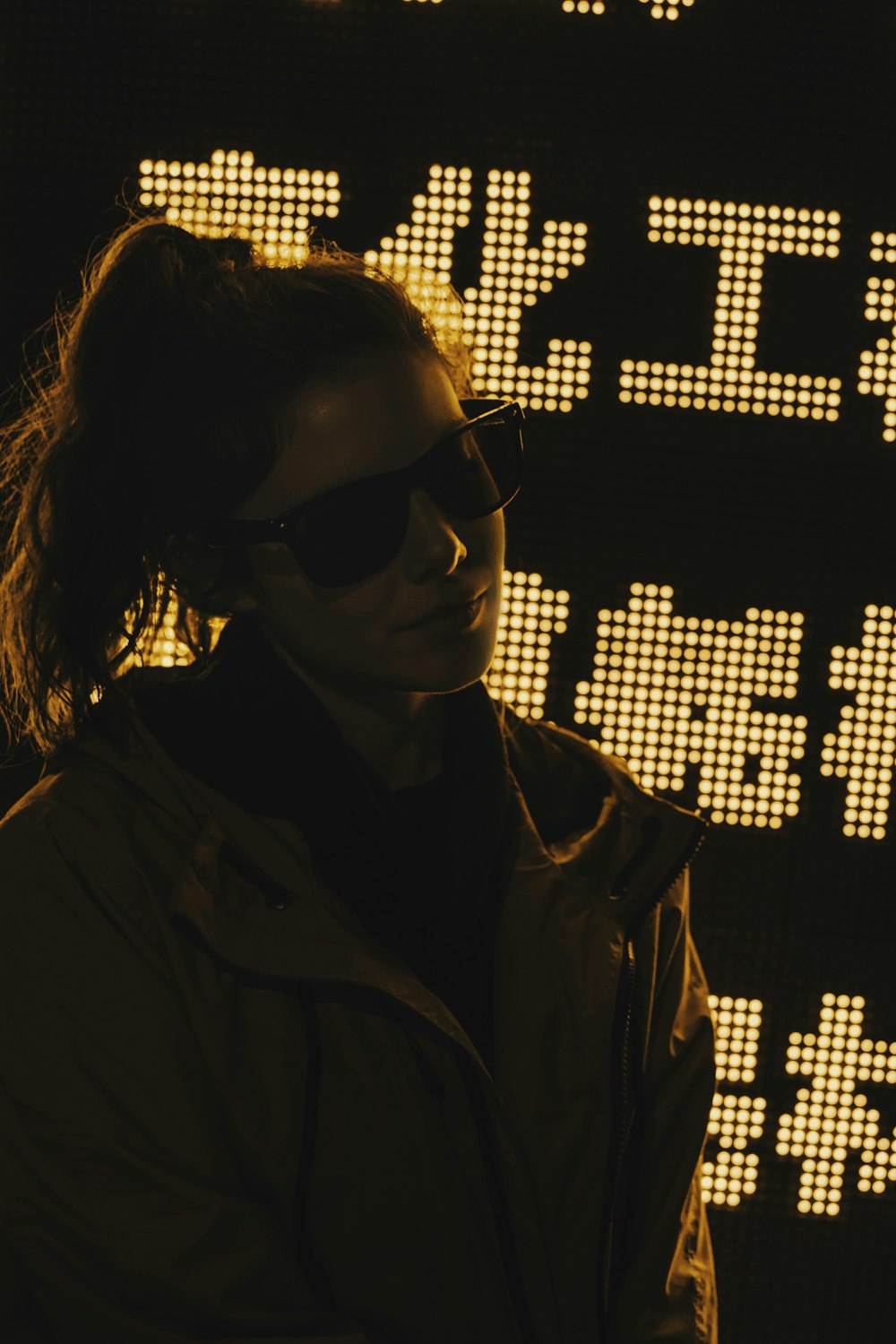 pony-tailed hair of woman in brown jacket wearing black sunglasses
