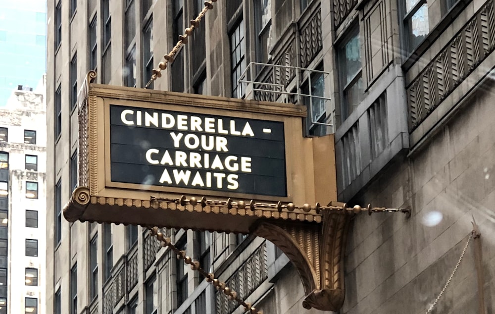 Cinderella your carriage awaits word signage mounted on concrete building
