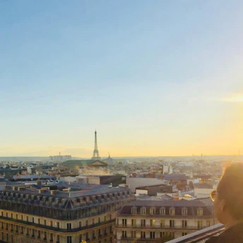 A stunning aerial view of Paris at sunset, showcasing the Eiffel Tower and Seine River glowing warmly.