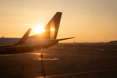 man walking under jet plane at the tarmac during sunset