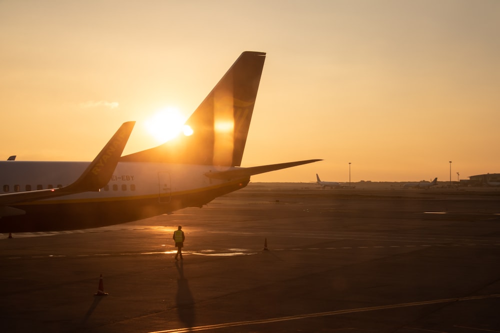 man walking under jet plane at the tarmac during sunset