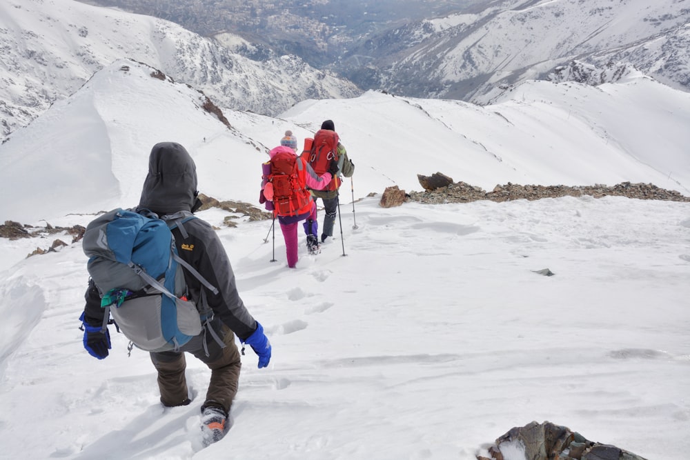 three person walking through snow