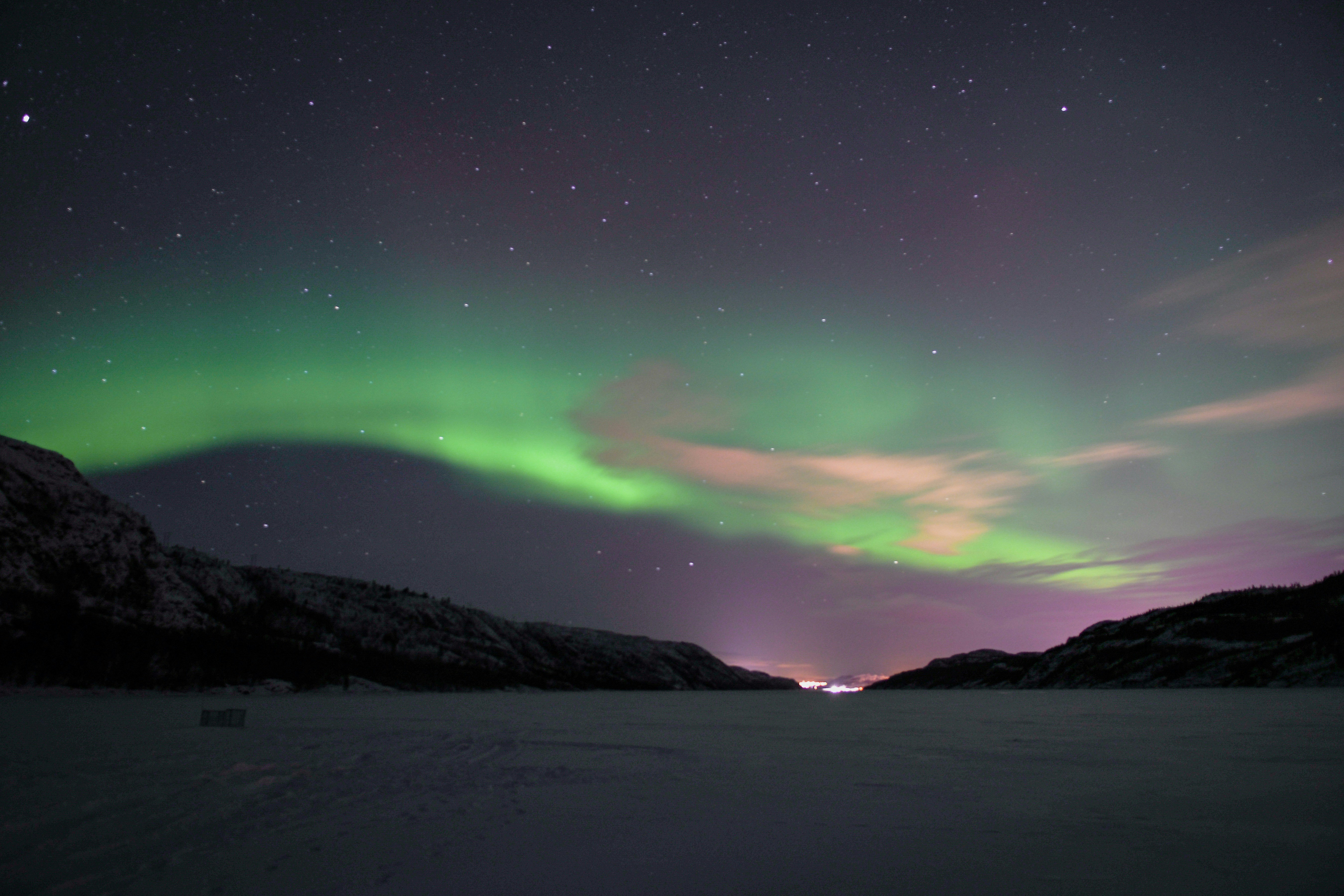 Northern lights aurora borealis in vivid green and purple over snowy landscape