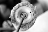 A close-up of a traditional spindle used for spinning cotton fibers. The image captures the detailed texture of the cotton wrapped around the spindle and the structural components of the tool.