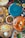 A variety of dishes presented on colorful plates, including a soup with herbs, flatbreads with toppings, and an assortment of vegetables. The vibrant arrangement of food is complemented by condiments such as sauces and spices scattered around.