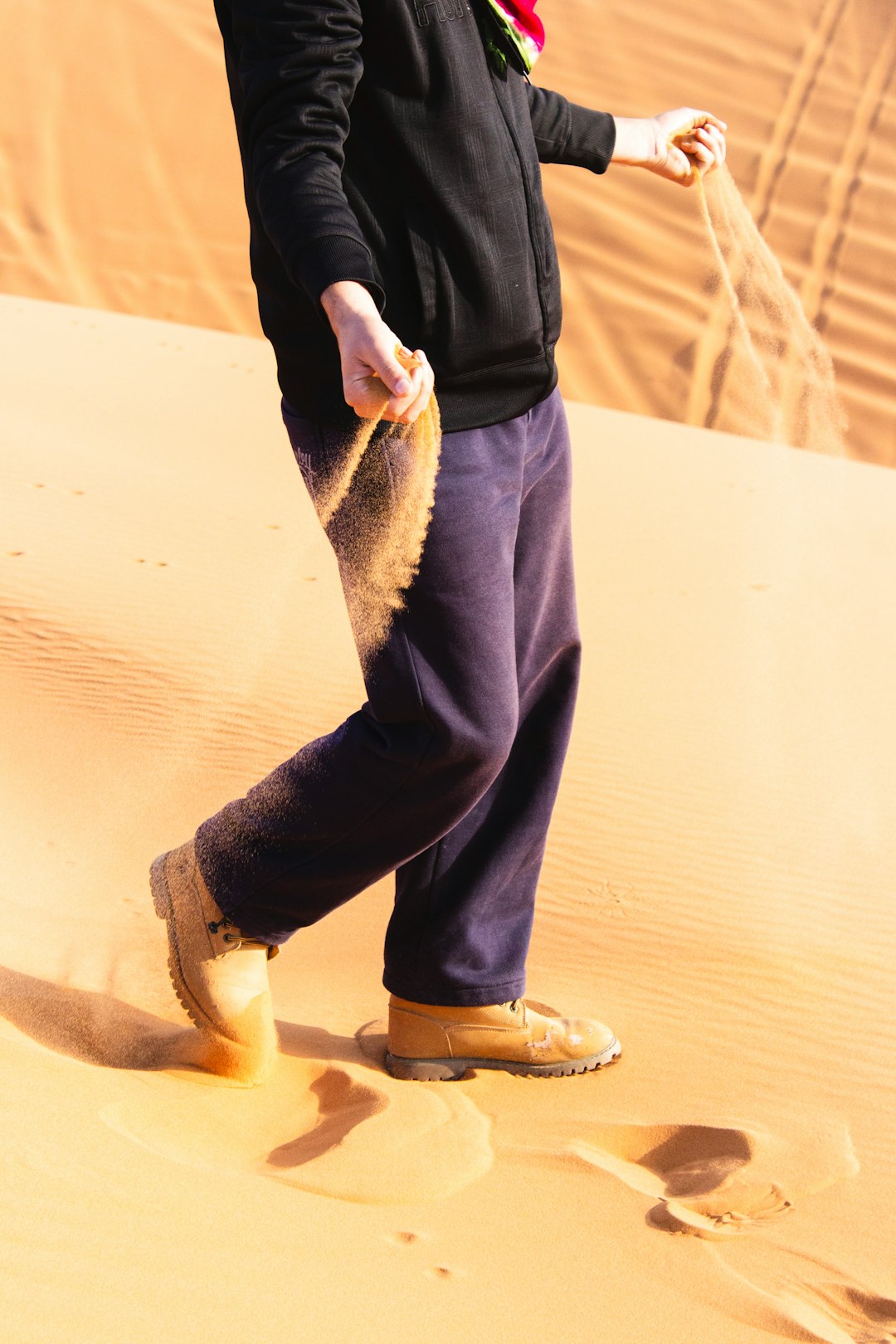 person standing on sand dune while holding sand