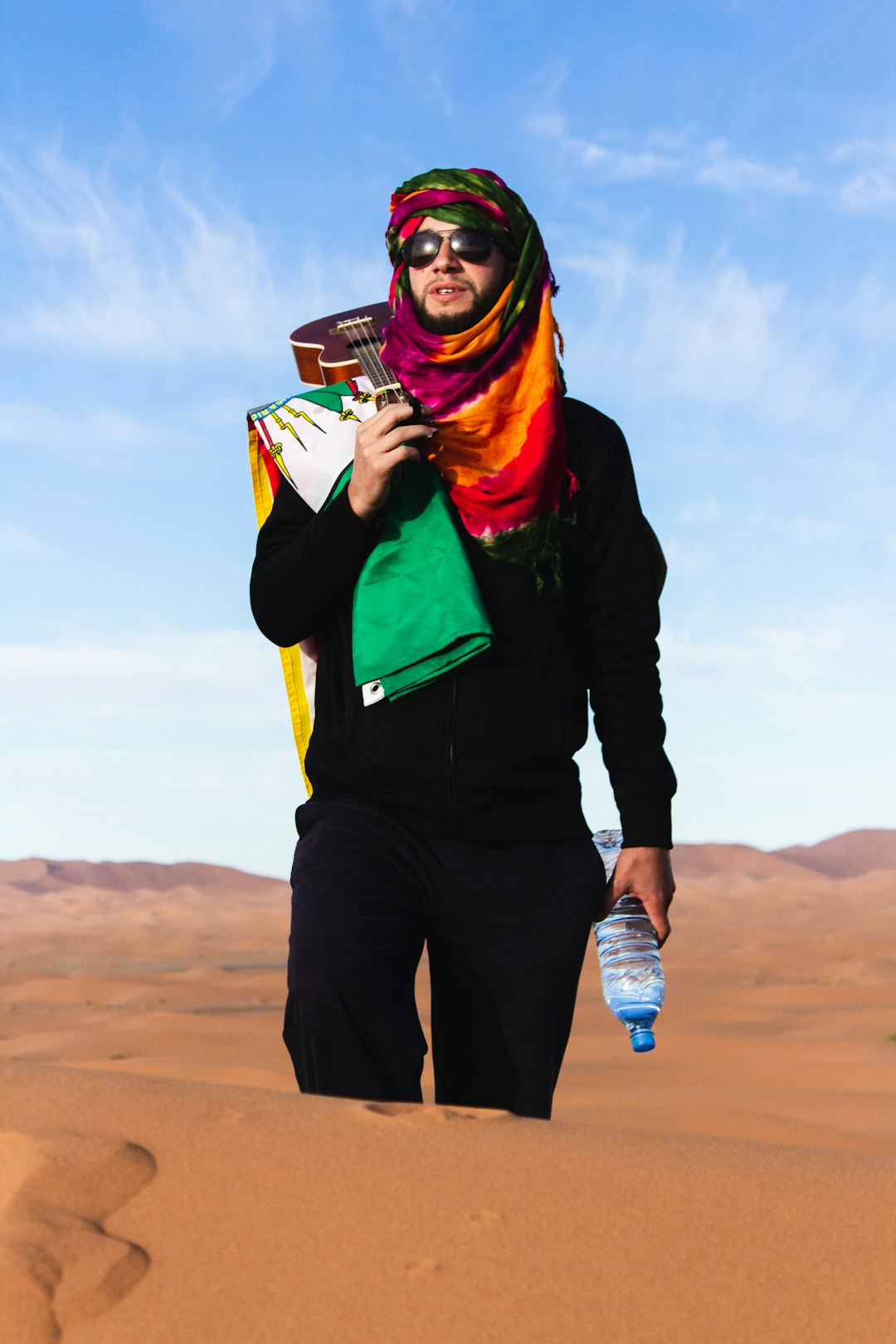 man waking at desert holding bottled water