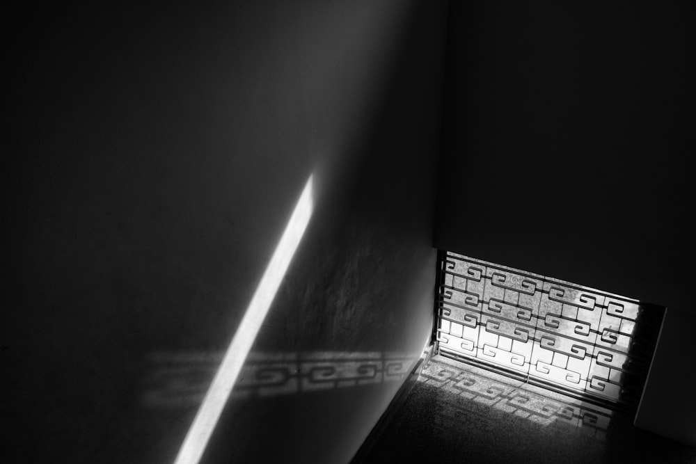 a black and white photo of a light coming through a window