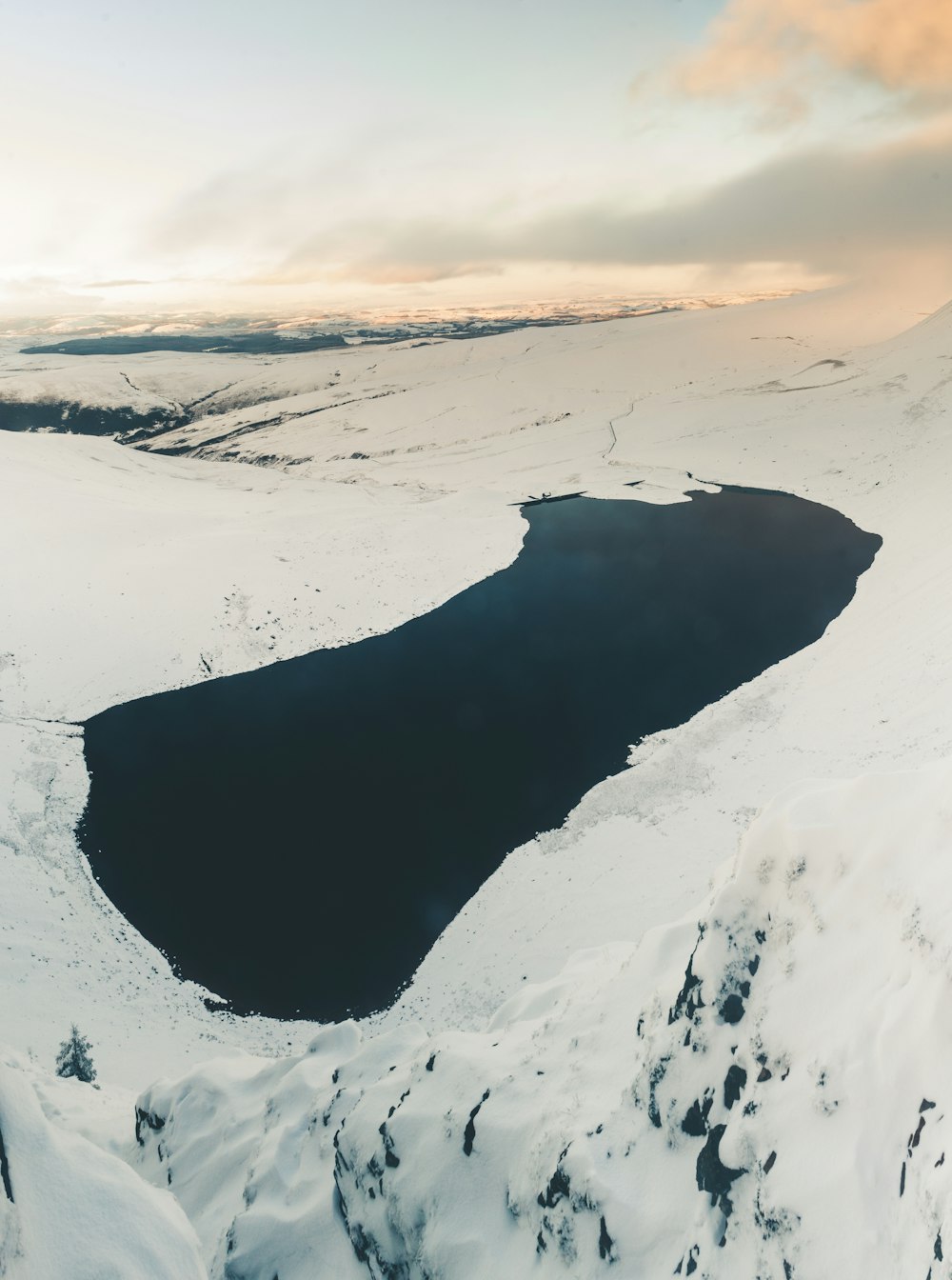 Cuerpo de agua tranquilo rodeado de terreno montañoso cubierto de nieve durante el día