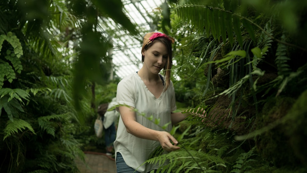 selective focus photography of woman standing beside Boston fern plant