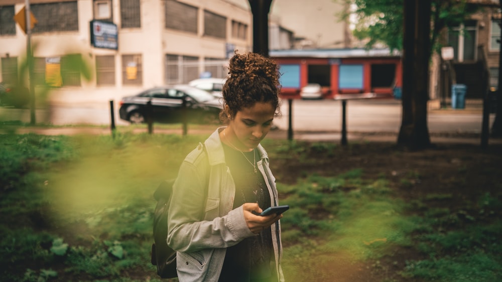 una donna in piedi nell'erba che guarda il suo cellulare