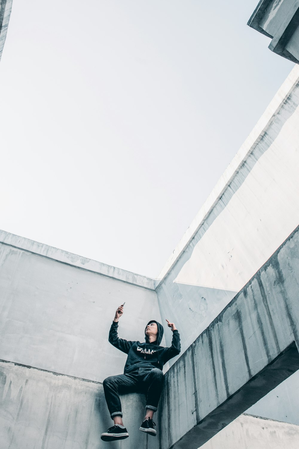 man sitting by ledge of building during daytime