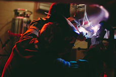 person welding on metal inside lighted building