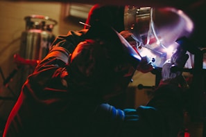 person welding on metal inside lighted building