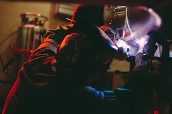 person welding on metal inside lighted building