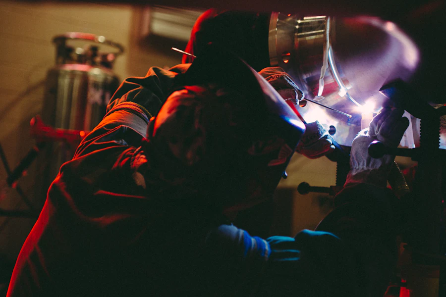 Welder joining stainless steel components with bright arc light in a fabrication shop