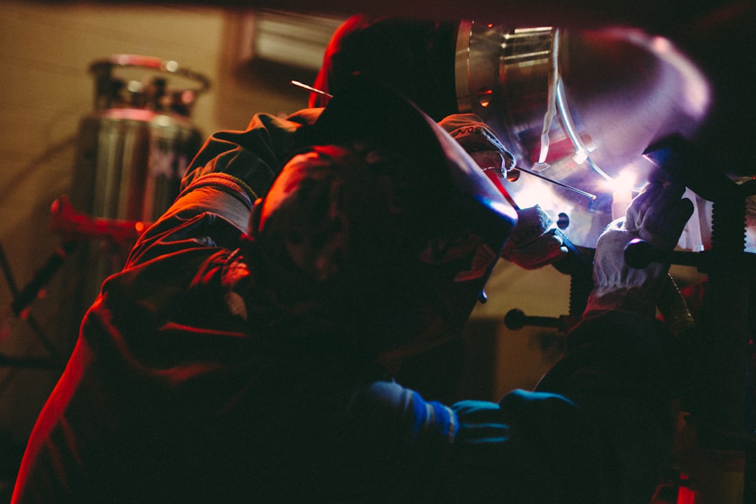 person welding on metal inside lighted building,