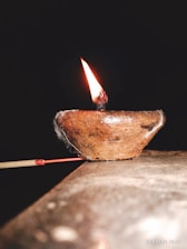Close-up of a traditional lamp lit beside a window, casting warm light on sacred scriptures.