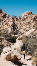 Hiker walking along dry desert trail under a bright blue sky