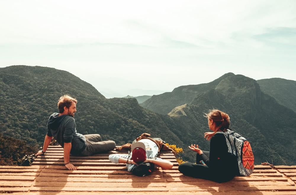 três pessoas com vista para as montanhas