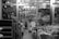 A cluttered store display features a wide assortment of kitchenware items, including stacks of pots, pans, and plates. The store is organized with shelves and racks, displaying items both hanging and stacked. The environment appears busy and densely packed, with various utensils and containers visible throughout.