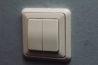 Close-up of a sleek smart switch glowing softly with a subtle blue accent in a minimalist room.