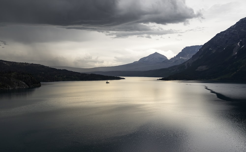 cuerpo de agua tranquilo cerca de la montaña bajo la formación de nubes blancas