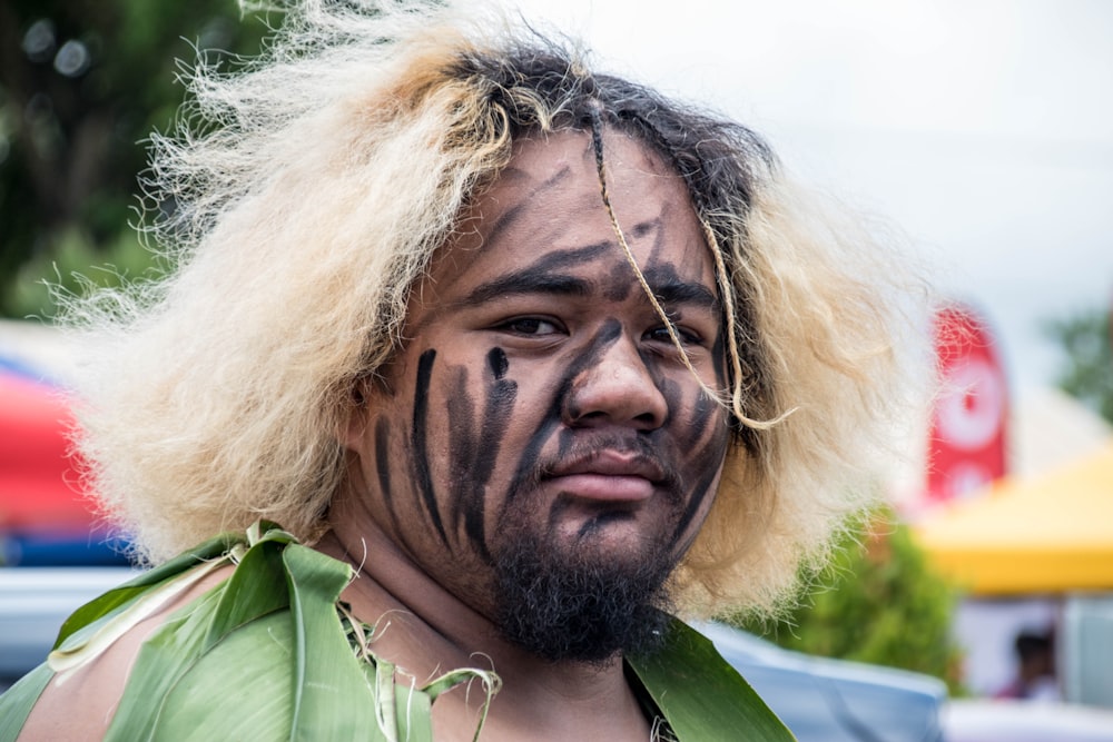 man with black face paint and blonde hair during daytime