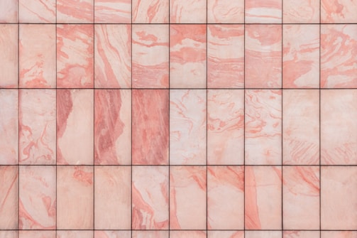 A grid of marble tiles with a pink and white swirling pattern, each tile showing unique variations in color and texture.