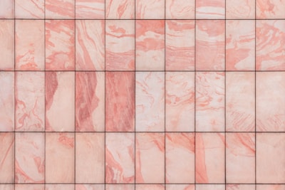 A grid of marble tiles with a pink and white swirling pattern, each tile showing unique variations in color and texture.