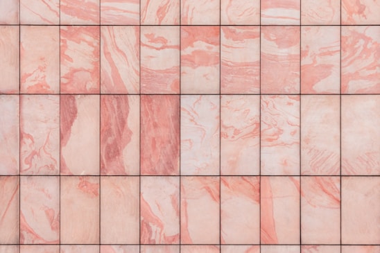 A grid of marble tiles with a pink and white swirling pattern, each tile showing unique variations in color and texture.