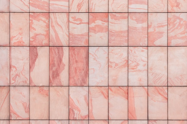 A grid of marble tiles with a pink and white swirling pattern, each tile showing unique variations in color and texture.