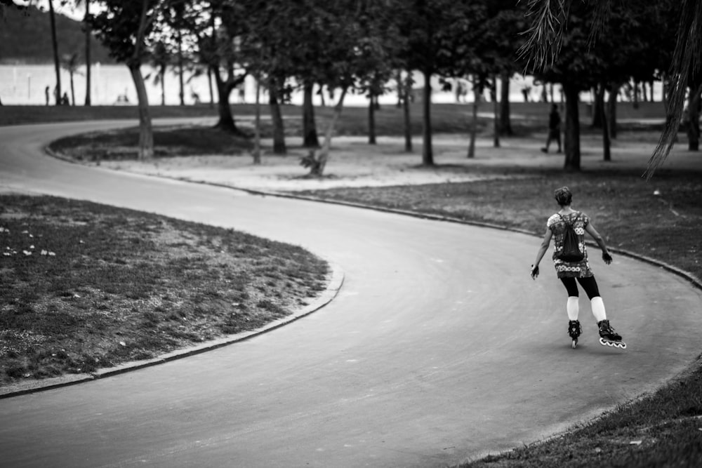 grayscale photography of girl in inline skates on road